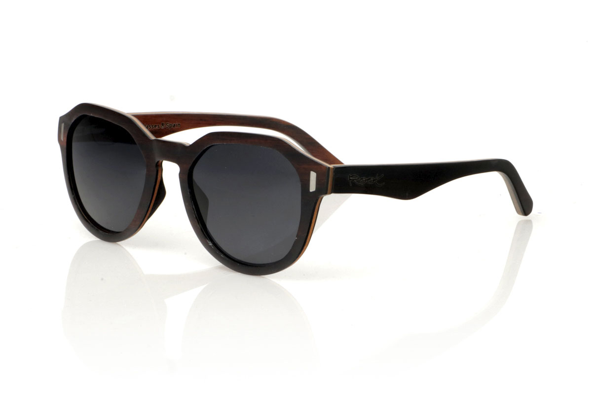 Wood eyewear of Ebony IZARO. IZARO wooden sunglasses are an expression of style and craftsmanship, made entirely of laminated ebony wood both outside and inside, with an intermediate layer of maple wood that provides a clear and striking contrast. The distinctive black and brown grain of the ebony is perfectly complemented by the distinctive hexagonal shape on the brow, while the silver metallic inlays on the sides add a touch of elegance and sophistication. With measurements of 145x50 and a caliber of 51, the IZARO are presented as a perfect option for those looking to stand out with a unique accessory that combines the natural beauty of wood with an innovative design. for Wholesale & Retail | Root Sunglasses® 